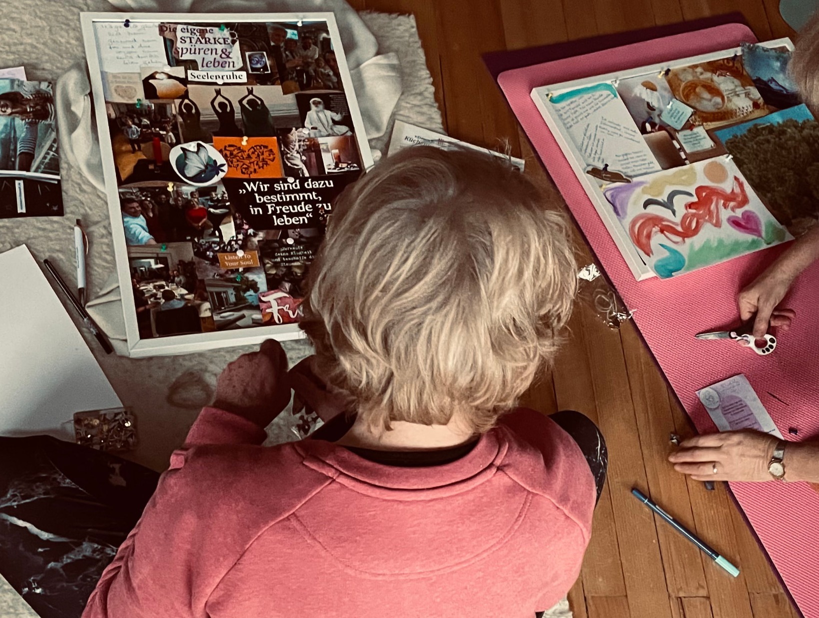Zwei Teilnehmerinnen gestalten ihre Vision Boards auf dem Boden